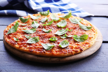 Pizza with basil on wooden table, closeup
