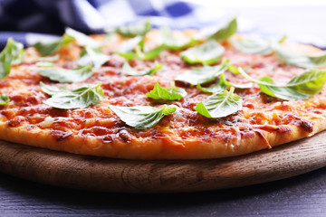 Pizza with basil on wooden table, closeup
