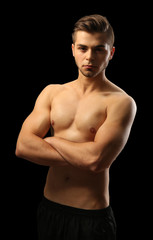 Naklejka premium Muscle young man on dark background