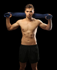 Fototapeta na wymiar Muscle young man holding towel on dark background