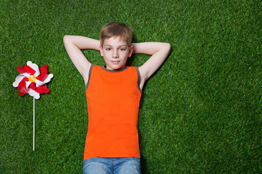 Boy Lying With Pinwheel  On Green Grass