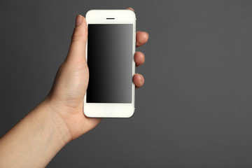 Hand holding mobile smart phone on gray background