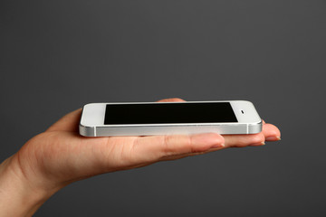 Hand holding mobile smart phone on gray background