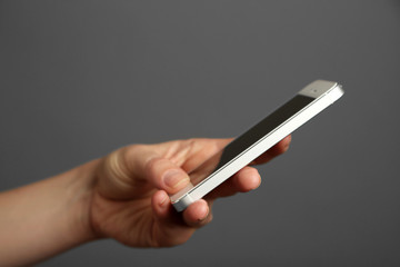 Hand holding mobile smart phone on gray background