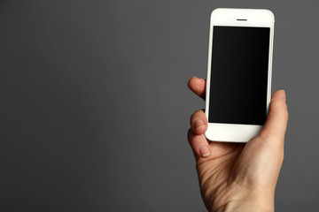 Hand holding mobile smart phone on gray background