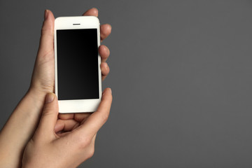 Hands holding mobile smart phone on gray background