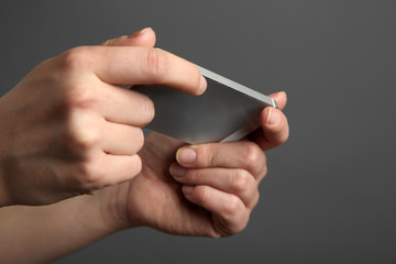 Hands holding mobile smart phone on gray background