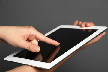Hands holding tablet on gray background