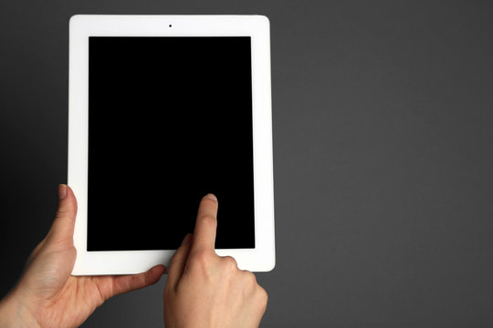 Hands holding tablet on gray background