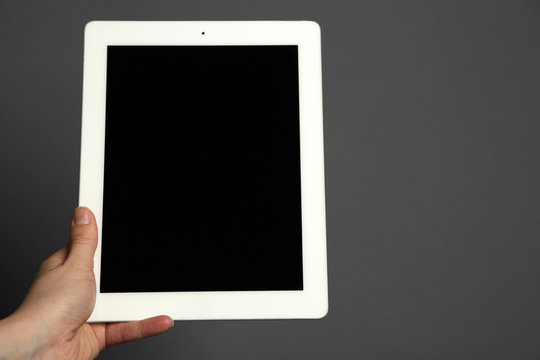 Hand holding tablet on gray background
