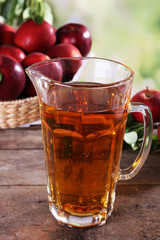 Full jug of apple juice and fruits on bright background