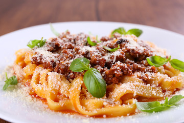 Pasta Bolognese with parmesan and basil on table close up