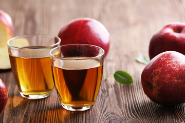 Glasses of apple juice and fruits on table close up