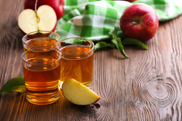 Glasses of apple juice and fruits on table close up
