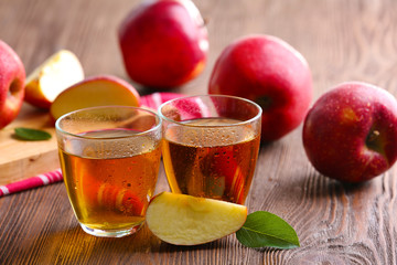Glasses of apple juice and fruits on table close up
