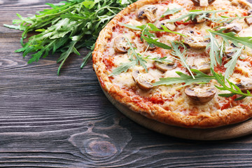 Tasty pizza with vegetables and arugula on wooden background