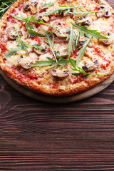 Tasty pizza with vegetables and arugula on wooden background