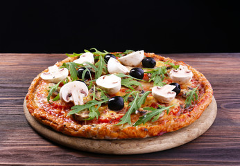 Tasty pizza with vegetables and arugula on black background