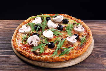 Tasty pizza with vegetables and arugula on black background