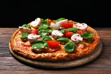 Tasty pizza with vegetables and basil on black background