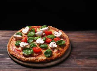 Tasty pizza with vegetables and basil on black background