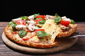 Tasty pizza with vegetables and basil on black background