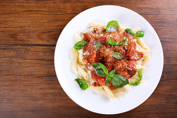 Pasta with tomato sauce and basil on wooden table close up