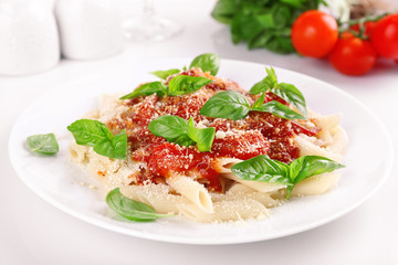 Pasta with tomato sauce and basil on table close up