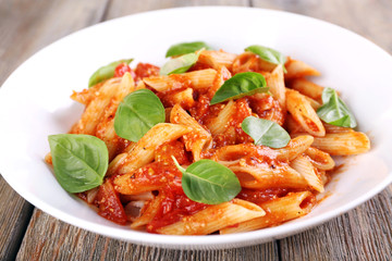 Pasta with tomato sauce and basil on table close up