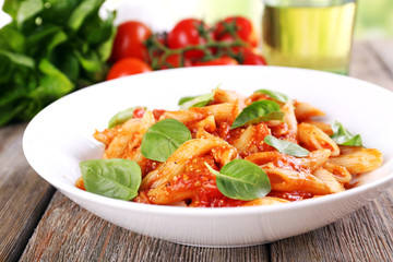Pasta with tomato sauce and basil on table close up