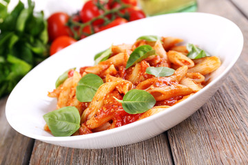 Pasta with tomato sauce and basil on table close up