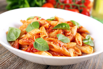 Pasta with tomato sauce and basil on table close up