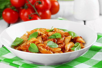 Pasta with tomato sauce and basil on table close up
