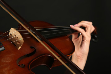 Violinist playing violin on dark background