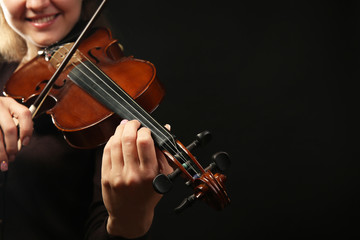 Violinist playing violin on dark background