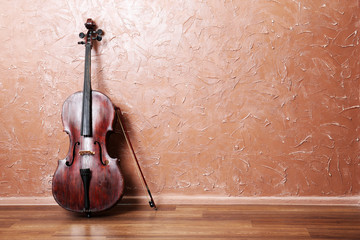 Classical cello and bow on brown wall background