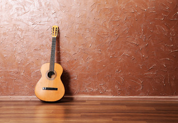 Classical acoustic guitar on brown wall background
