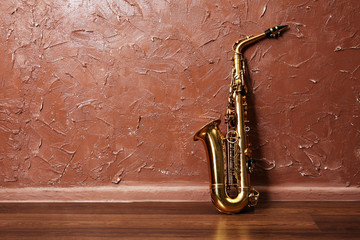Naklejka premium Golden saxophone on brown wall background