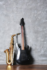 Electric guitar, flute and saxophone on gray wall background