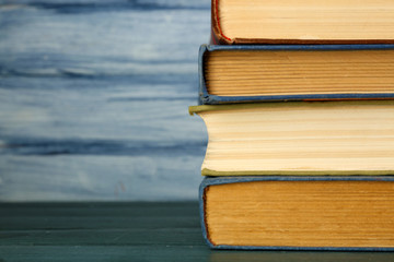 Stack of books on wooden table on blue wooden wall background