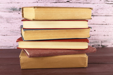 Stack of books on wooden table on pink wooden wall background