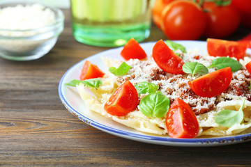 Pasta bolognese with cherry tomatoes in white plate on wooden table, closeup