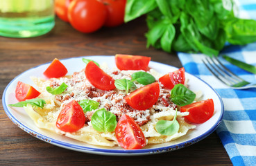 Pasta bolognese with cherry tomatoes in white plate on wooden table, closeup