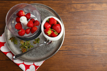 Ripe strawberries in blender on metal tray on wooden table, top view