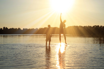 Glückliche junge Menschen laufen und springen am See beim Sonnenuntergang