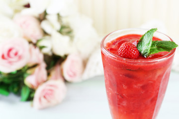 Strawberry dessert with ice in glass, on wooden table, on light background