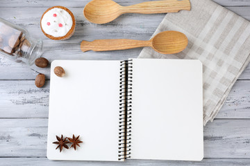 Open recipe book and tasty bakery on wooden background