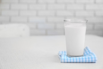 Glass of milk on wooden table, on bricks wall background