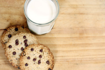 snack: glass of milk and chocolate chip cookies on wooden background
