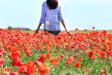 Woman walking on poppy field over blue sky background